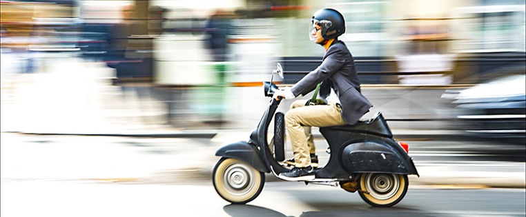Vespa Roller fährt im Straßenverkehr