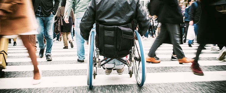 Mann im Rollstuhl fährt über Straße