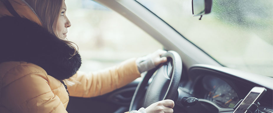 Frau mit Winterjacke fährt Auto