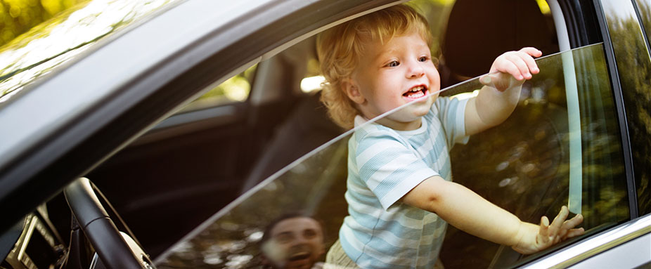 Kind spielt im Auto am offenen Fenster