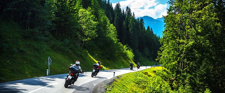 Gruppe von Motorradfahrern fährt auf einer Straße durch den Wald