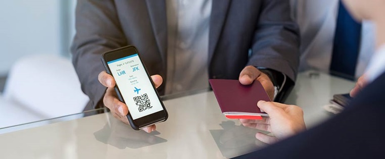 Mann zeigt Flughafenmitarbeiterin sein Online Ticket auf dem Handy