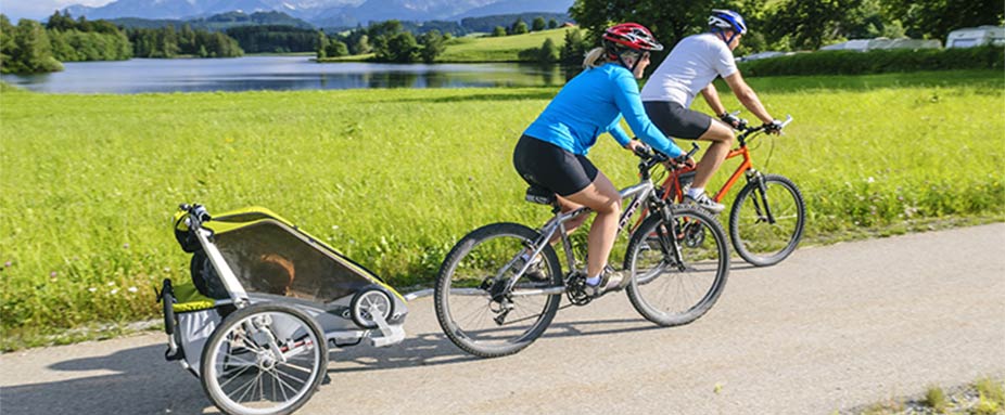 Frau fährt auf Fahrrad und zieht Fahrradanhänger