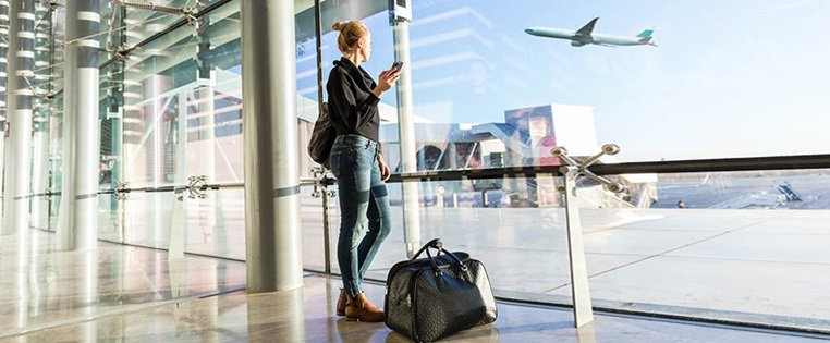 Frau steht am Flughafen und beobachtet Flugzeug