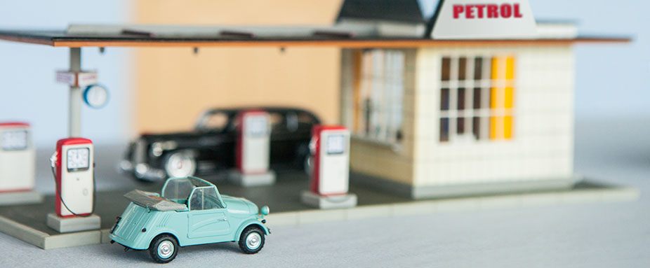 Spielzeugauto steht an einer Miniaturtankstelle