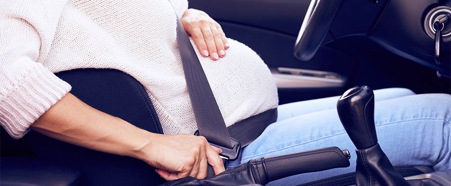 Schwangere Frau legt Sicherheitsgurt an