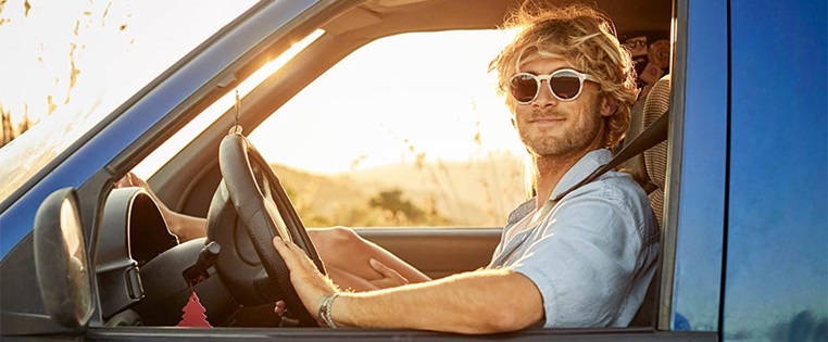 Junger Mann fährt mit Sonnenbrille Auto