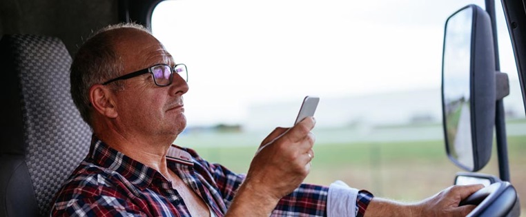 Lkw Fahrer mit Handy am Steuer