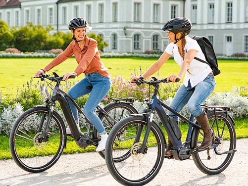 Zwei Frauen fahren im Park auf E-Bikes