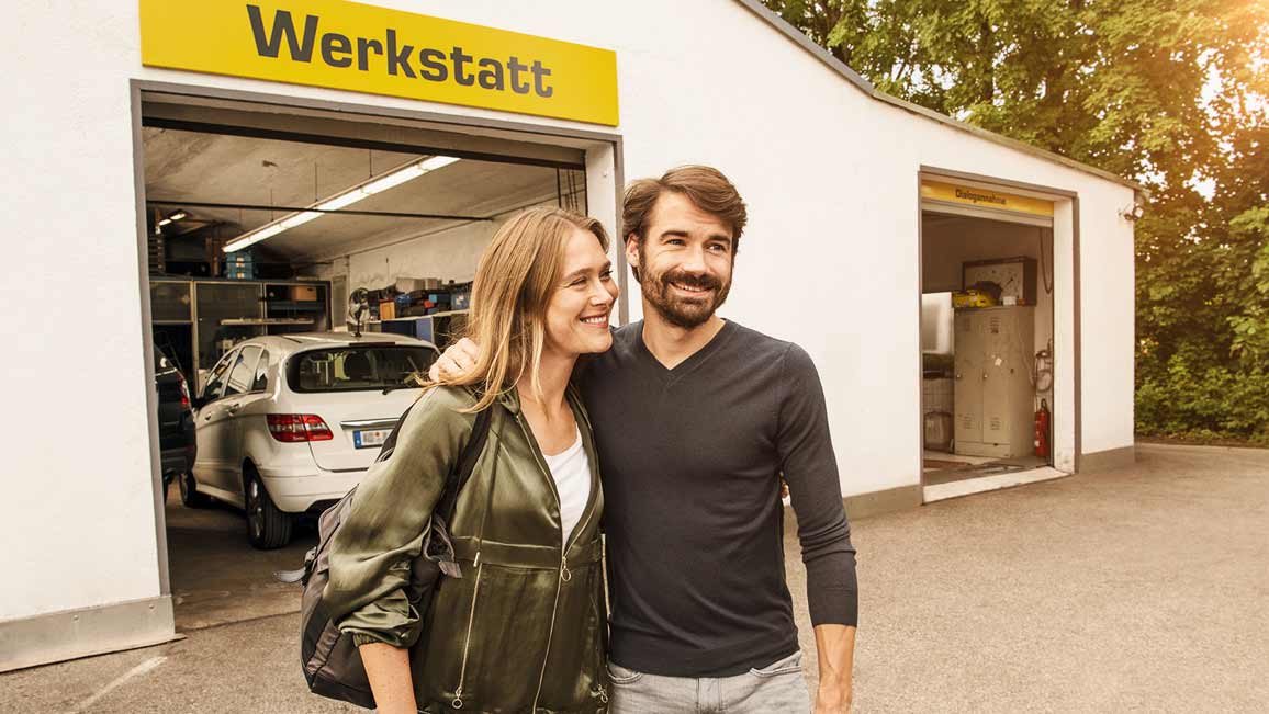 Ein Paar steht vor einer Werkstatt und ist glücklich