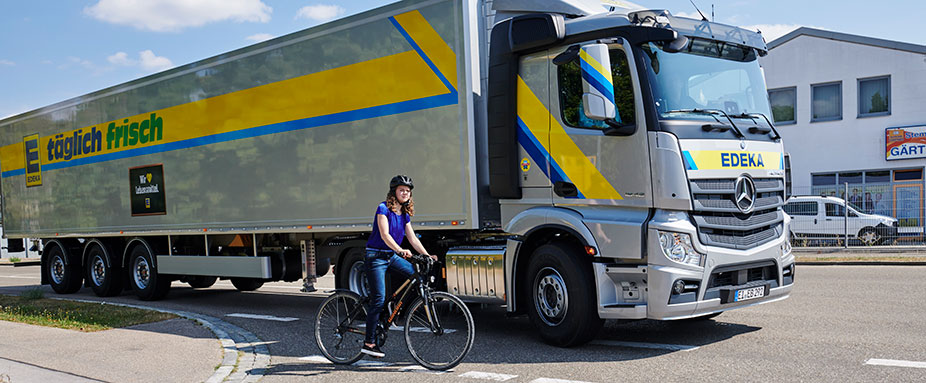Edeka LKW biegt ab, Fahrradfahrer fährtv vorbei