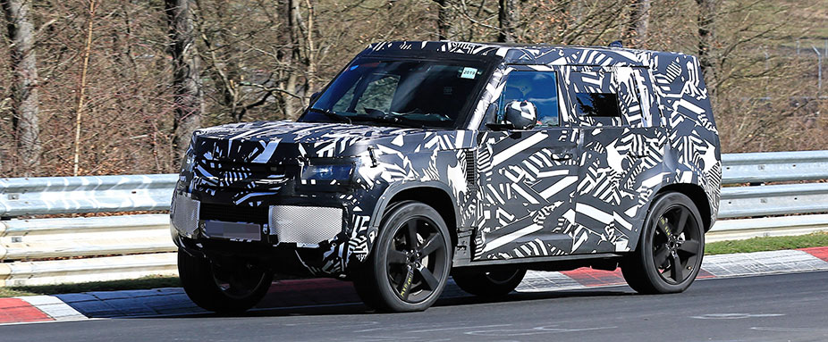 Landrover Defender fahrend, schräg vorne
