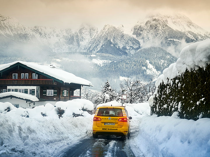 ADAC Pannenhelfer vor Bergkulisse im Schnee