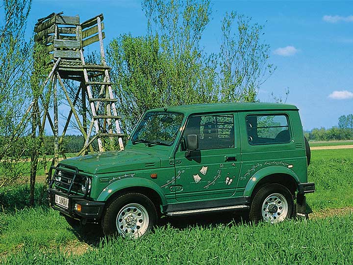 Suzuki Jimny steht vor einem Hochstand