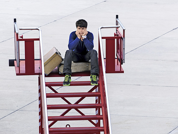 Ein Mann sitzt auf der Treppe zu einem Flugzeug auf seinen Koffern