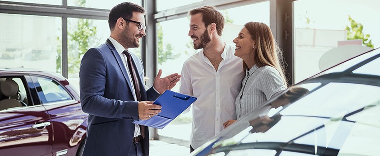 Ehepaar im Gespräch mit einem Autohändler