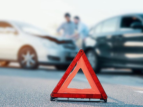 Warndreieck, im Hintergrund ein Unfall