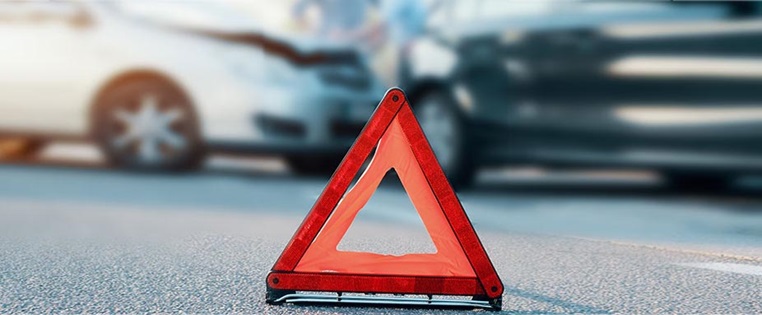 Warndreieck, im Hintergrund ein Unfall