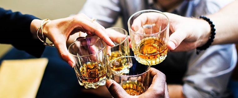 Hände mit Whiskeygläsern stoßen an