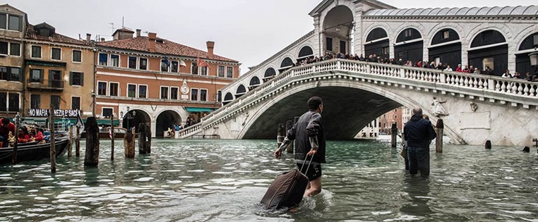 Tourist zieht Koffer durch einen überschwemmten Kanal in Venedig bei Jahrhunderthochwasser