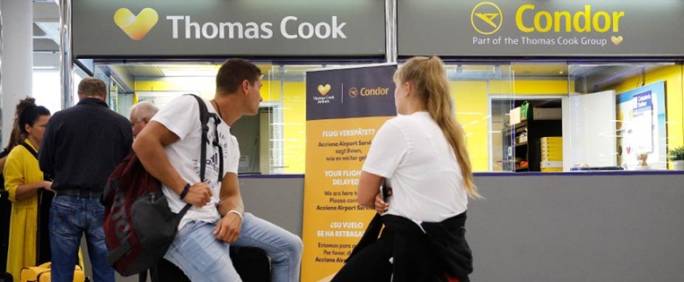 Wartende Passagiere vor dem Thomas Cook Schalter am FLughafen
