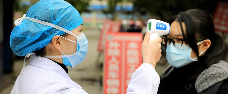 Ärztin vollzieht in China auf der Straße an einer Frau einen Fieber-Check zur Prävention der Verbreitung des Corona Virus