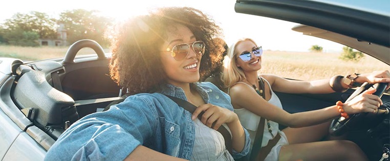 Zwei junge Frauen genießen den Sommer im Cabrio