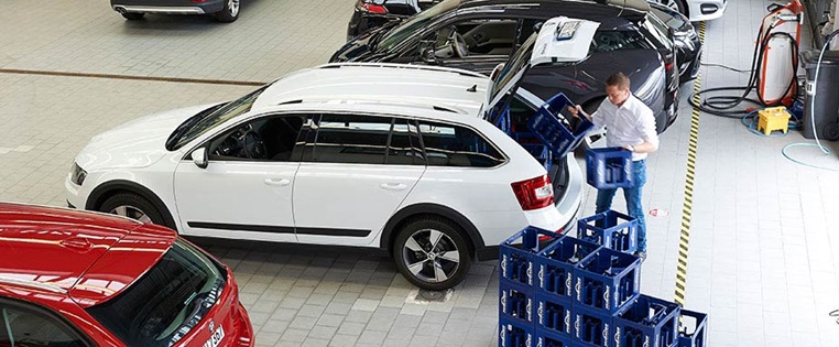 Autos stehen in einer Halle. Wasserkästen werden eingeladen