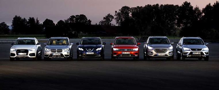Autos stehen bei Abendrost in einer Reihe mit erleuchteten LED Scheinwerfern