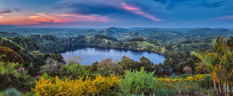 See in Uganda in Berglandschaft mit vielen Blumen und Pflanzen umgeben