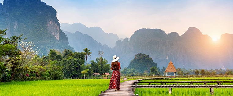 Frau läuft auf Holzweg in Reisfeld in Vang Vieng in Laos