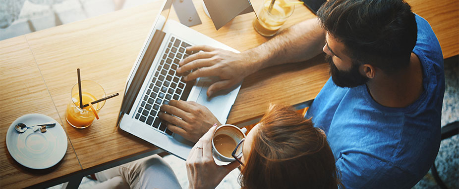 Mann und Frau schauen auf Laptop in einem Cafe