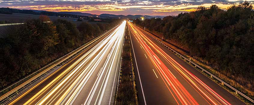 Straße bei Dämmerung mit Langzeitbelichtung der Autolichter