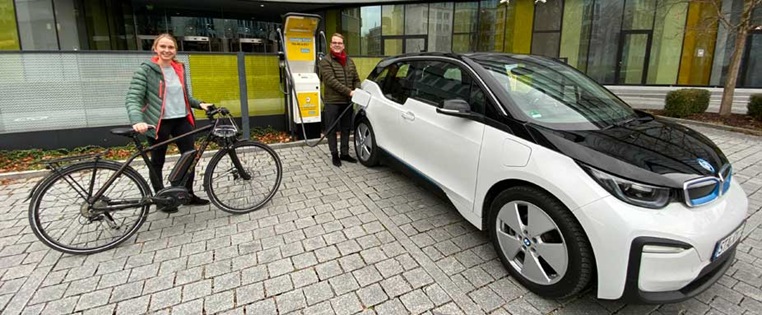 Klara Deeken mit E-Bike und Max Betz mit BMW i3 vor der Ladesäule an der ADAC Zentrale
